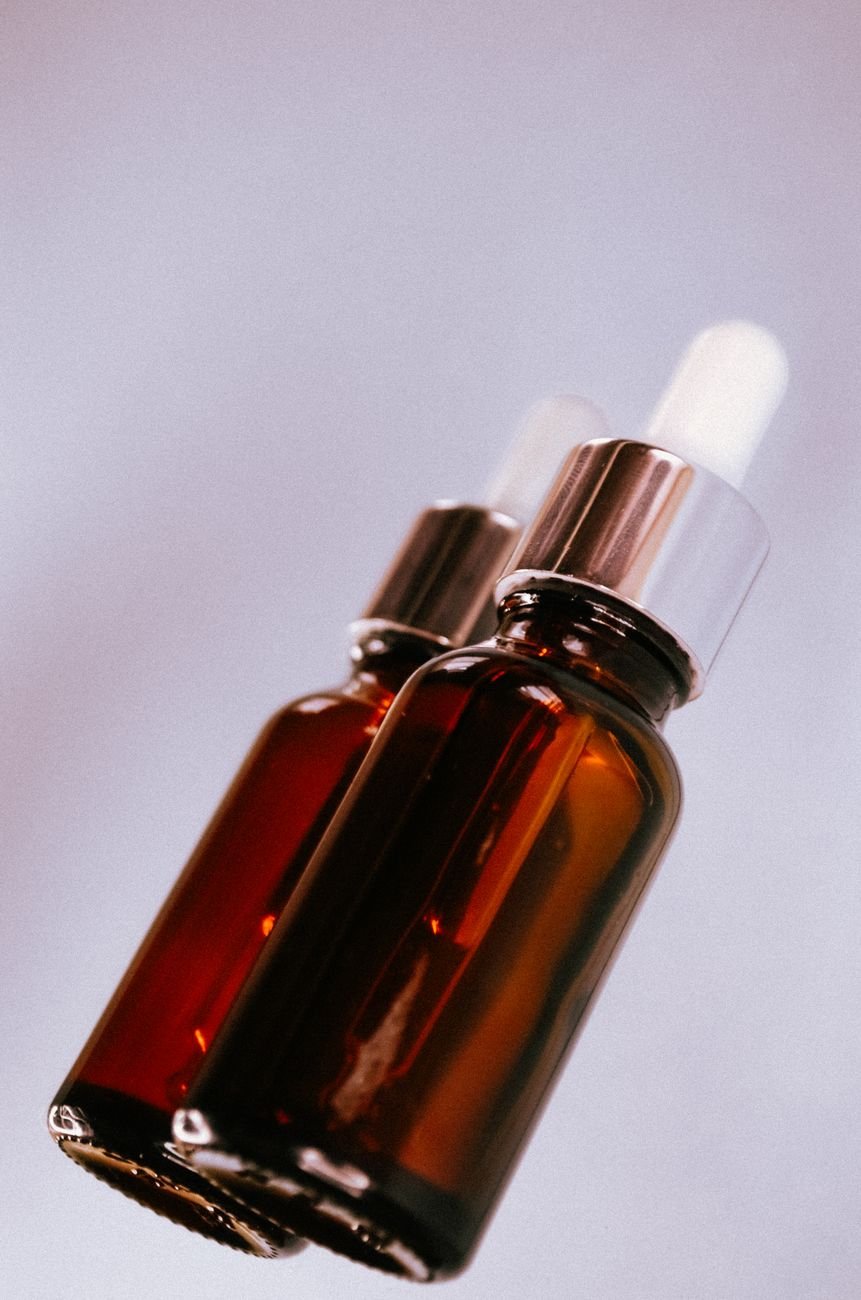 Elegant amber glass dropper bottles on a pastel background — skincare product detail