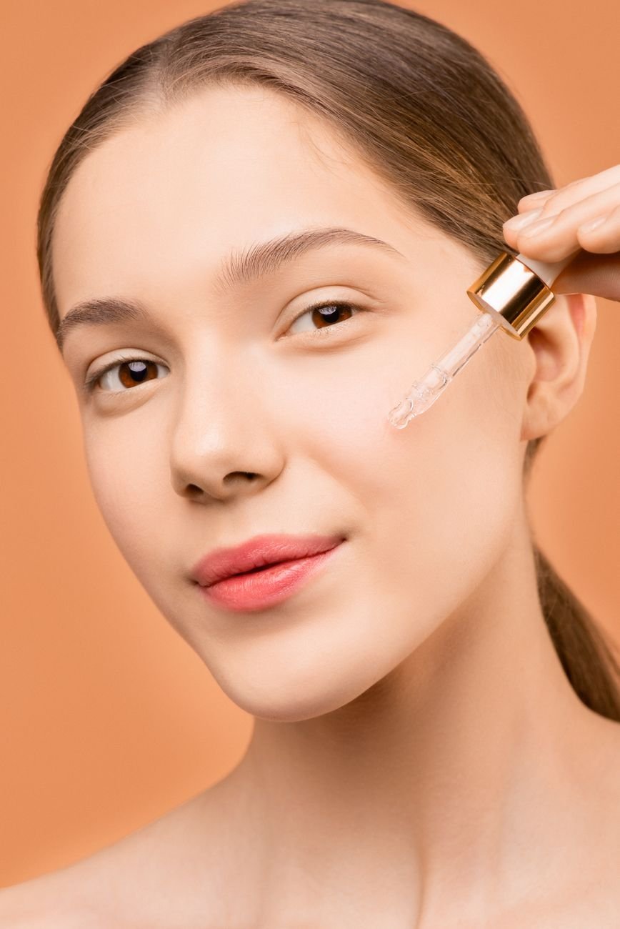 Close-up of a young woman using a dropper to apply facial serum